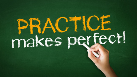 A person drawing and pointing at a Practice Makes Perfect Chalk Illustrationの写真素材