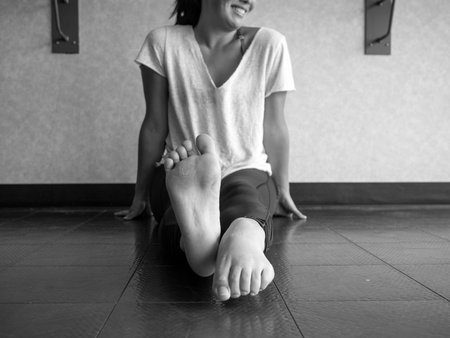 Black and white version of Smiling dancer warming up her feet with alternating pointing and flexing