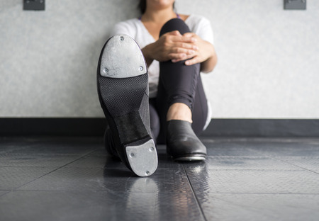 Tap dancer lounging and showing her tap shoesの写真素材