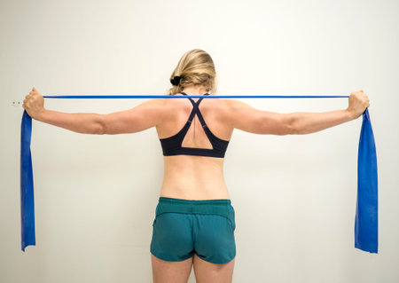 Strong female athlete using a resistance theraband to strengthen her arms muscles