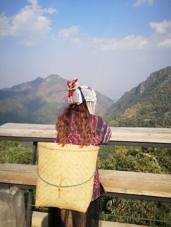 Akha tribe woman costume sitted on the bench with mountain viewの写真素材