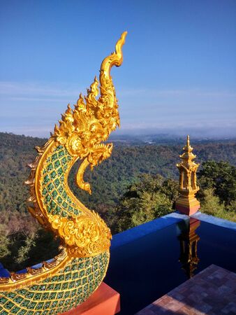 A beautiful golden serpent in a temple on a high mountain Overlooking the sea of ââmist on clear sky day. Wat Doi Pra Chan Lampang Thailandの写真素材