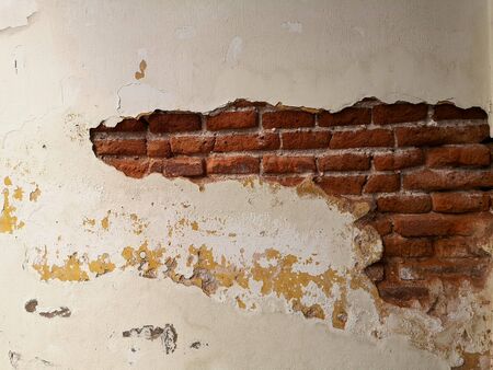 Old cement wall that had been broken over time to see the red bricks inside.の写真素材
