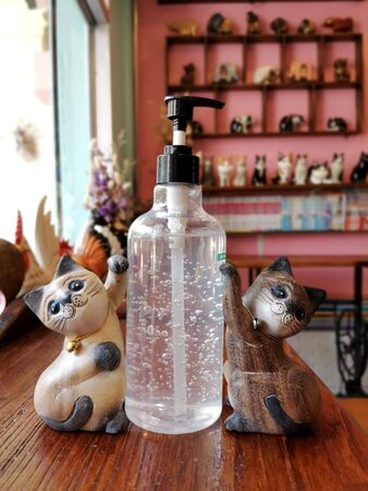 Alcohol gel wash your hands to protect Kovid-19 with cats made of wood as decoration In a beautiful cafe in blurred backgroundの写真素材