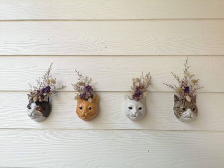 Ceramic cat head with flowers to decorate the white wooden wallの写真素材
