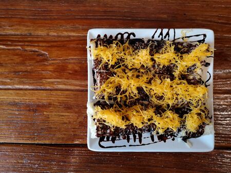 Modern Roti topped with chocolate And Foi Thong dessert. It is perfect for eating with tea or coffee on a white plate on a wooden table.の写真素材