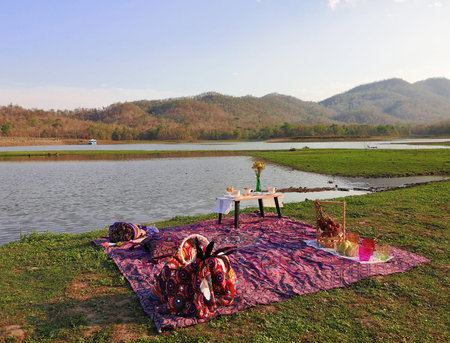 Picnic sets are placed beside the reservoir and the mountains background.の写真素材