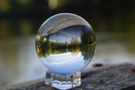 Crystal ball on a wooden table with a lake in the background.の写真素材