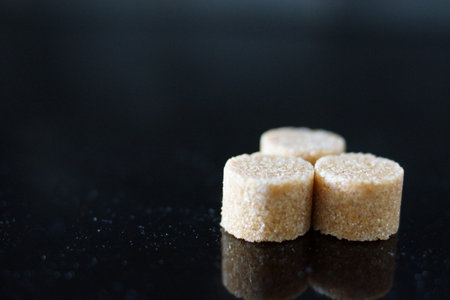 Brown sugar cubes shimmer under the light, revealing their perfect cubic shapes and delicate crystals.の写真素材