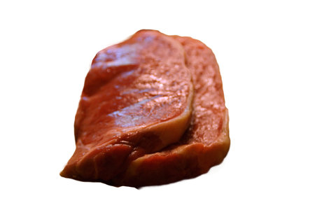 A generous cut of ribeye steak, beautifully marbled, remains on a rustic wooden board.の写真素材