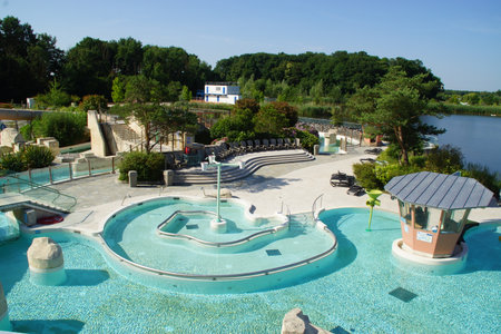 Beneath a radiant sky, a large public swimming pool stretches out, lined with relaxed swimmers and colorful lounge chairs. France.の写真素材