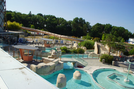 Beneath a radiant sky, a large public swimming pool stretches out, lined with relaxed swimmers and colorful lounge chairs. France.の写真素材