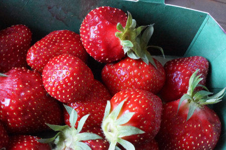 Fresh, juicy strawberries glowing in vibrant red, gently arranged on a light background that highlights their glossy texture and natural deliciousness.の写真素材