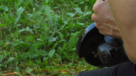 A man saws iron fittings with a grinder.