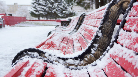 red park benches covered with snow.の写真素材