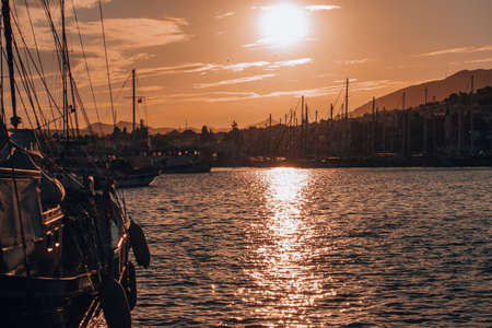 Beautiful sunset view of a marina. Boats and seaside town silhouette landscape.