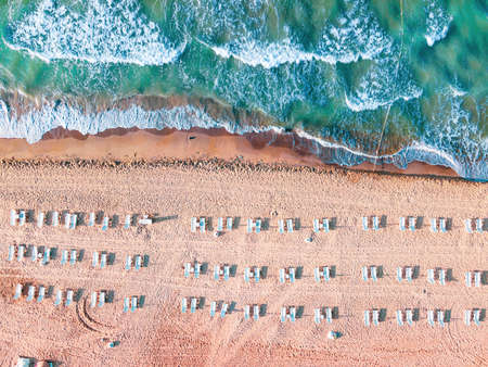 Aerial drone top down shot of empty beach and clean blue sea. Beautiful beach with empty sunbeds. Summer holiday background view.の写真素材