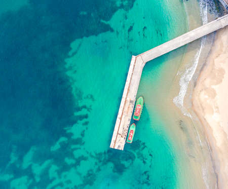 Wooden dock and two boats with blue sea. Aerial drone view of beautiful sea and beach. Summer...
