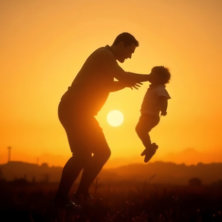 Silhouette of father playing with his daughter on the field at sunsetの素材