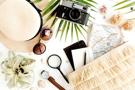 Traveler accessories on white background with retro camera, straw hat, bag, sunglasses, map and tropical palm leaf.の写真素材