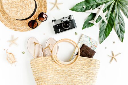 Womans beach accessories: rattan bag, straw hat, tropical palm leaves, airplane on white background. The concept of travel. Summer background.の写真素材