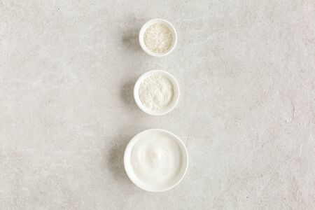 Three various natural spa cosmetics products in a bowl: facial cream, cosmetic clay, sea salt on gray marble background. Skincare concept.の写真素材