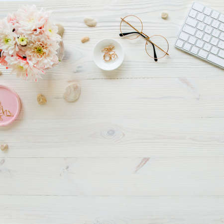 Top view office desk. Workspace with, computer, chrysanthemum, clipboard. Womens fashion accessories...