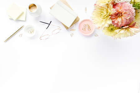 Flat lay home office desk. Female workspace with pink and beige roses flowers, accessories, gold and pink diary, white wooden background. Top viewの写真素材