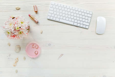 Top view office desk. Workspace with, computer, chrysanthemum, clipboard. Womens fashion accessories isolated on white wooden background. Flat layの写真素材