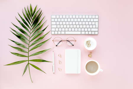 Office table desk with computer, green leaves palm, clipboard. Top view. Flat lay. Home office workspace. Womens accessories on pink background.の写真素材