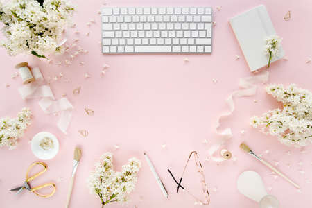 Office table desk with computer, lilac, clipboard. magazines. Top view Flat lay. Home office workspace. Womens fashion accessories on pink backgroundの写真素材