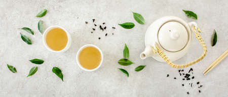 Herbal tea with two white tea cups and teapot, with green tea leaves. Flat lay, top view. Tea conceptの写真素材