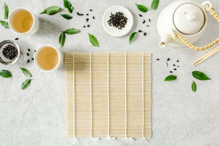 Herbal tea with two white tea cups and teapot, with green tea leaves. Flat lay, top view. Tea...