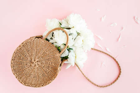 White bouquet of peonies in a straw bag on pink background. Minimal floral concept greeting card. Flat lay, top view.の写真素材