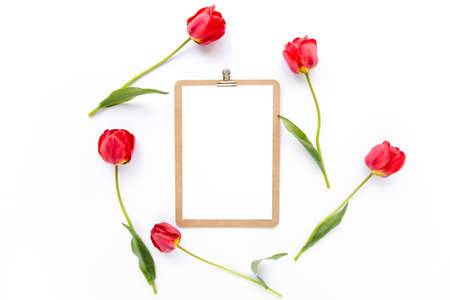 Clipboard mock up with beautiful red tulips isolated on white background. Flat lay, top view. Minimalistic office desk. Beauty blog concept.の写真素材