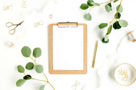 Workspace with clipboard and leaf eucalyptus on white background. Flat lay of home office desk, top view.の写真素材