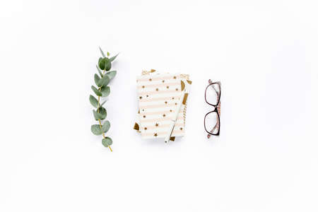 diary, pen, green leaves eucalyptus and glasses on white background. flat lay, top view