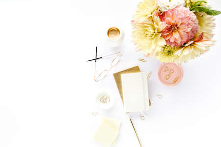 Flat lay womens office desk. Female workspace with yellow dahlias and roses flowers, accessories, golden diary, white wooden background. Top view.の写真素材