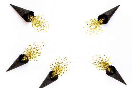 Black waffle cones with golden confetti tinsel isolated on white background. Flat lay, top view...