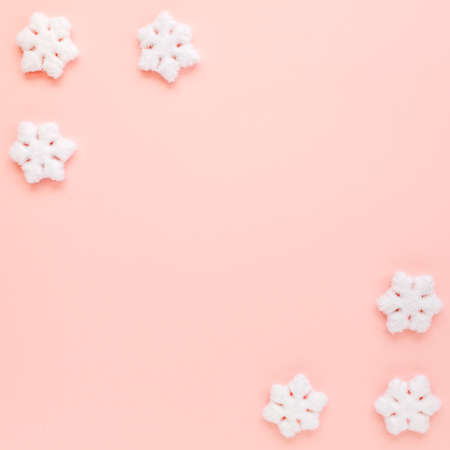 Christmas frame with white christmas snowflakes on pink background. Christmas composition, wallpaper. Flat lay, top viewの写真素材