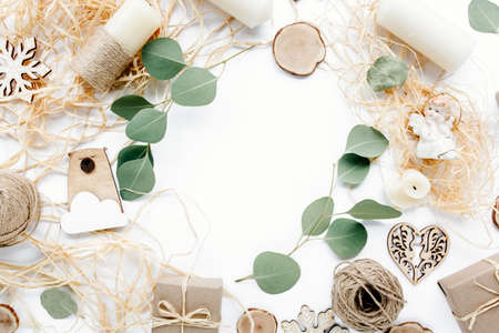 christmas toys and craft boxes. creative arrangement frame of craft boxes and green branches eucalyptus on white background. flat lay, top viewの写真素材