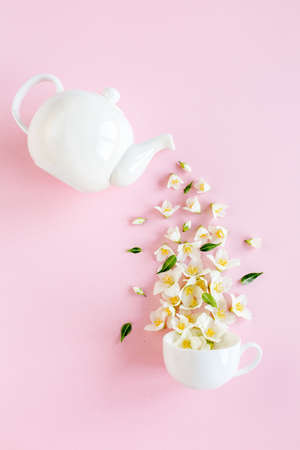 Creative layout of teapot and tea Cup with Jasmine flowers on a pink background. Jasmine tea.の写真素材