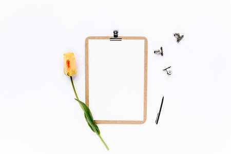 Clipboard mock up with beautiful yellow tulips isolated on white background. Flat lay, top view. Minimalistic office desk. Beauty blog concept.の写真素材