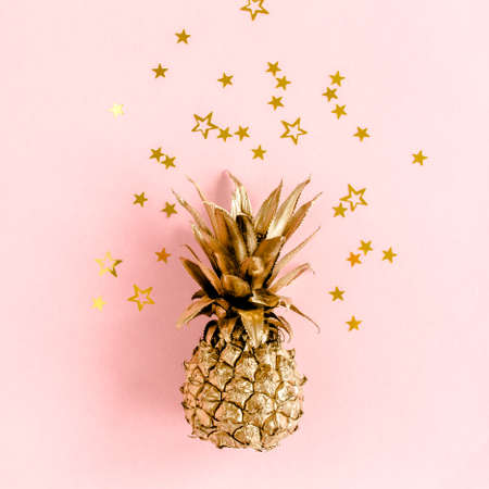 Top view golden pineapple covered golden confetti stars on pink background. Template blog social media. Minimal style. flat layの写真素材