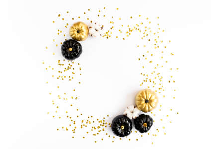 Gold frame decorated with black and gold Halloween pumpkin and tinsel with copy space for text. isolated on white background. Flat lay, top view.の写真素材