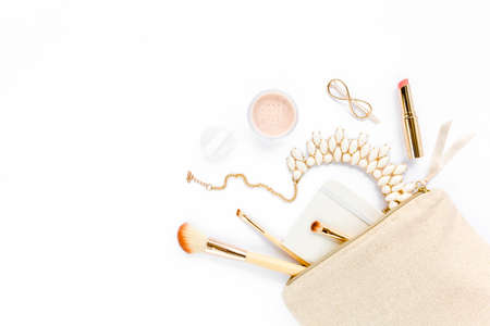 Beige cosmetic bag, makeup brushes, cosmetics, golden accessories on white background. Flat composition. magazines, social media. Top view. Flat lay.の写真素材