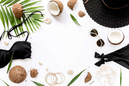 Feminine beige swimsuit beach accessories, tropical palm leaf branches, coconuts on white background with empty space for text. Flat lay, top view.の写真素材