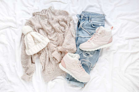 Woman clothes and accessories set on white background. Womens warm sweater, jeans, sneakers. Modern and outfit. Shopping concept. Flat lay, top view.の写真素材