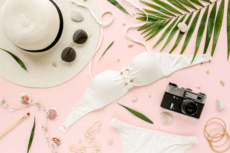 Feminine white swimsuit beach accessories, tropical palm leaf branches on pink background. Travel vacation concept. Summer background. Road frame setの写真素材