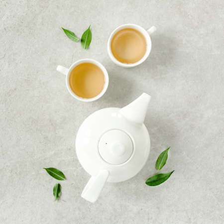 Herbal tea with two white tea cups and teapot, with green tea leaves. Flat lay, top view. Tea conceptの写真素材